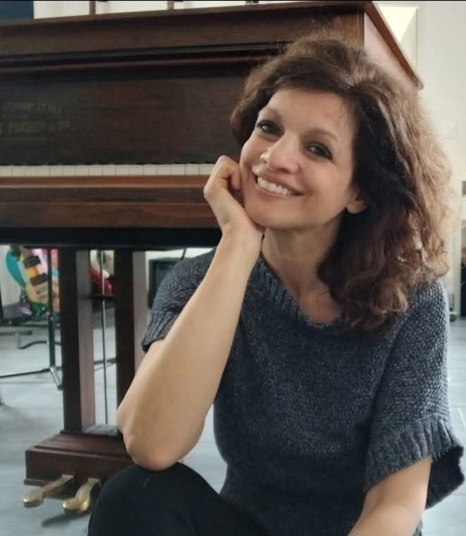 Nadège Mayer souriante, accoudée à son piano droit